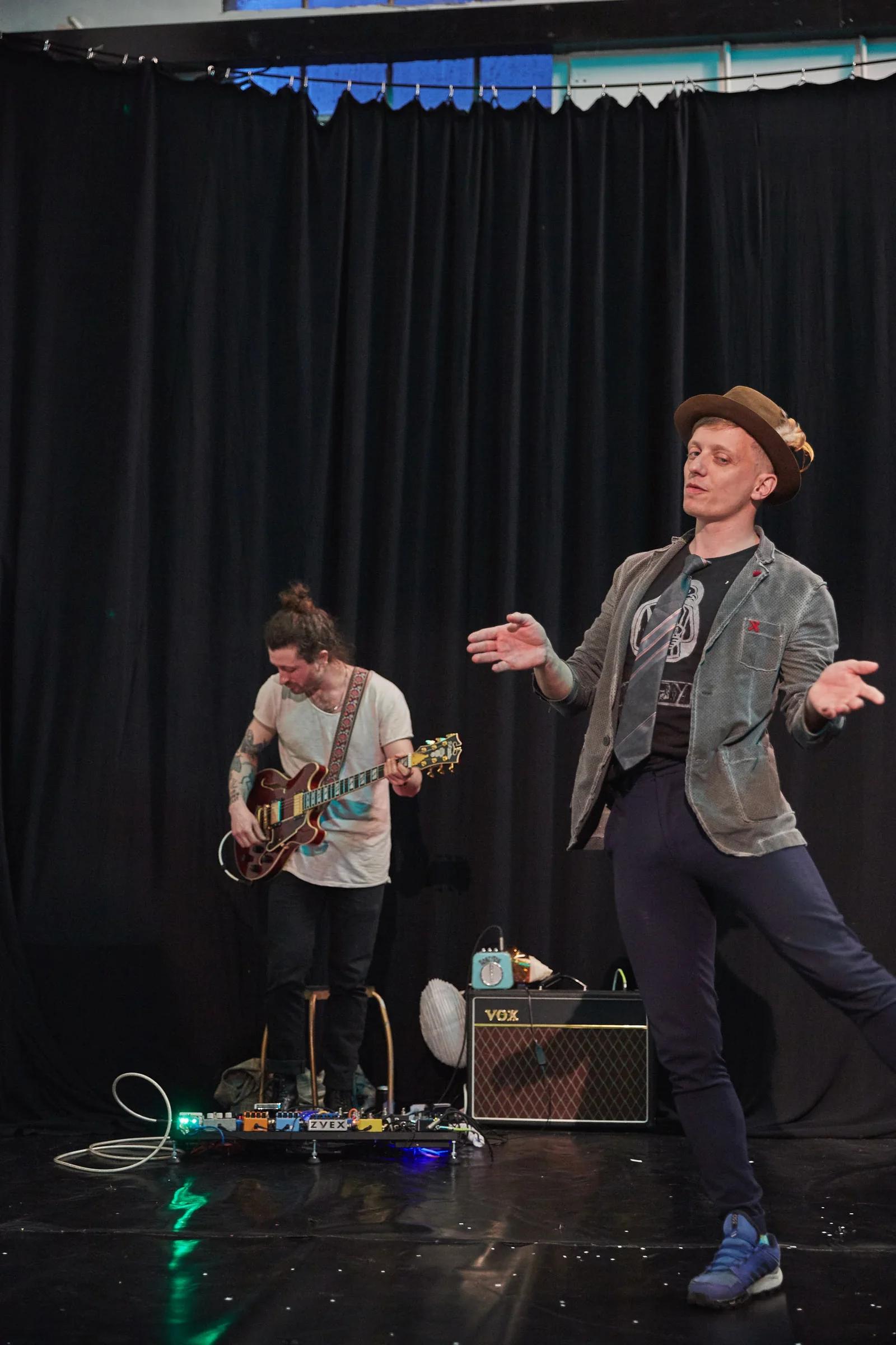 Live guitarist and clown performer on stage during a cabaret.
